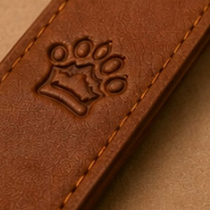 The paw and crown mark debossed into a cognac strap